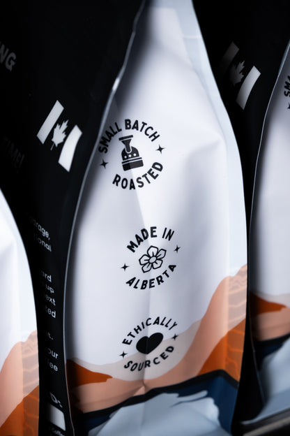 Three coffee bags with branding and text on a black background