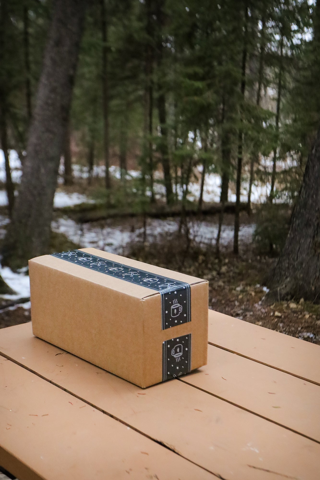 Cardboard box with blue tape on a wooden table in a forest setting