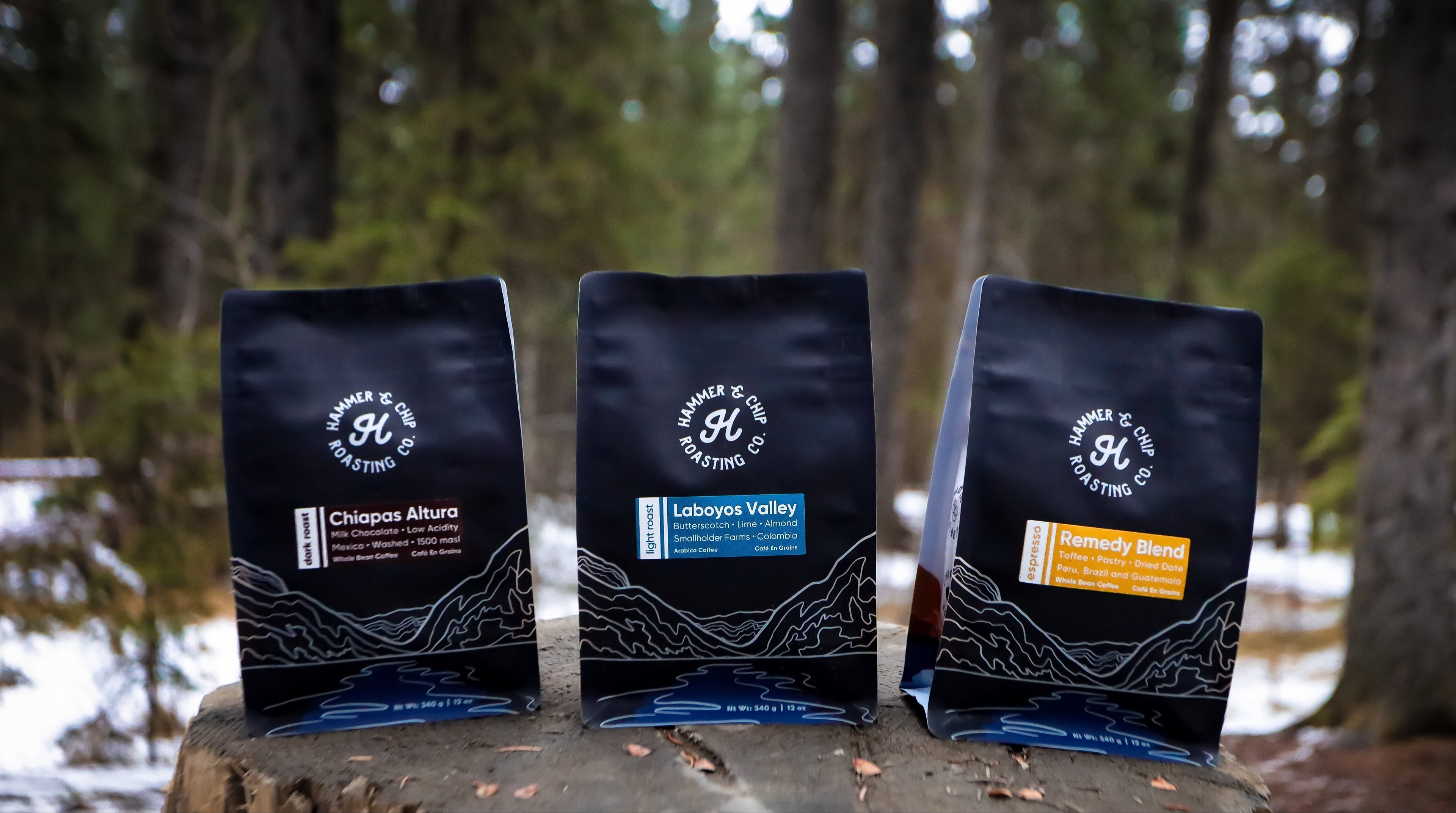 Three coffee packages on a wooden stump with a forest background