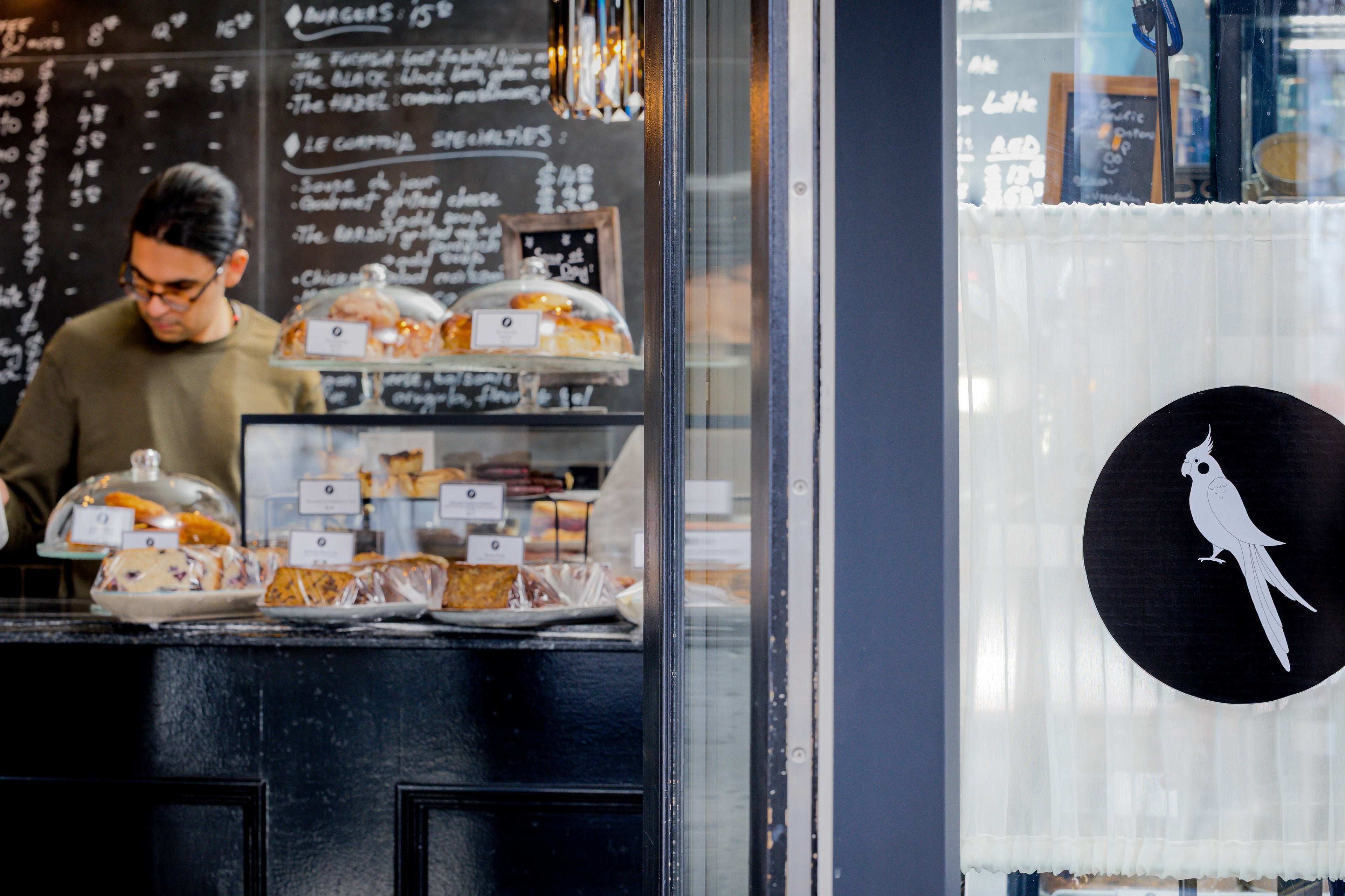 Person working behind a counter with food display in a cafe setting